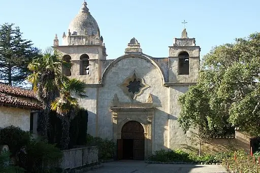 The stone facade and bell towers of the Carmel Mission