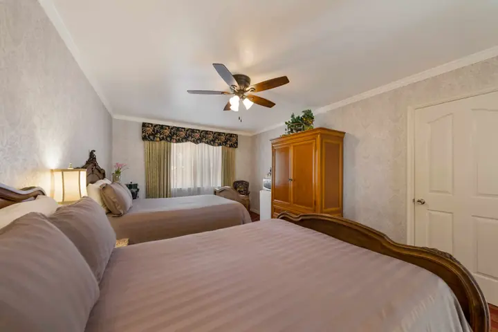Two double beds with striped bedspreads and a window valance