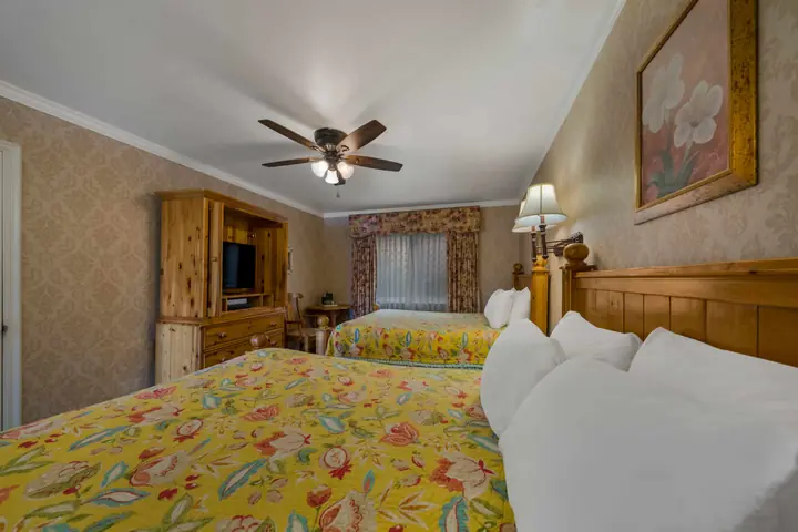 Two queen beds with floral bedspreads and a television cabinet