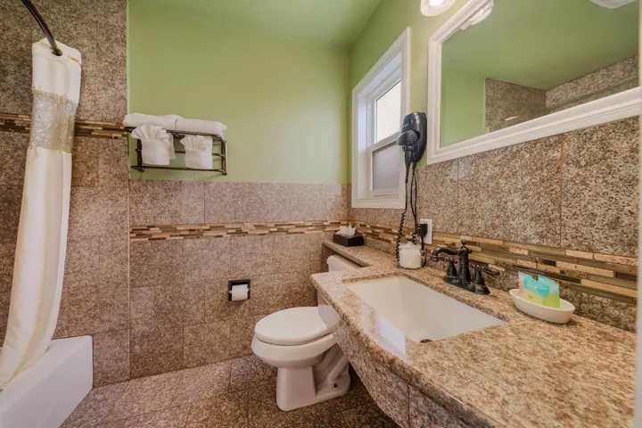 Suite bathroom with a granite vanity, tiled walls and a shower