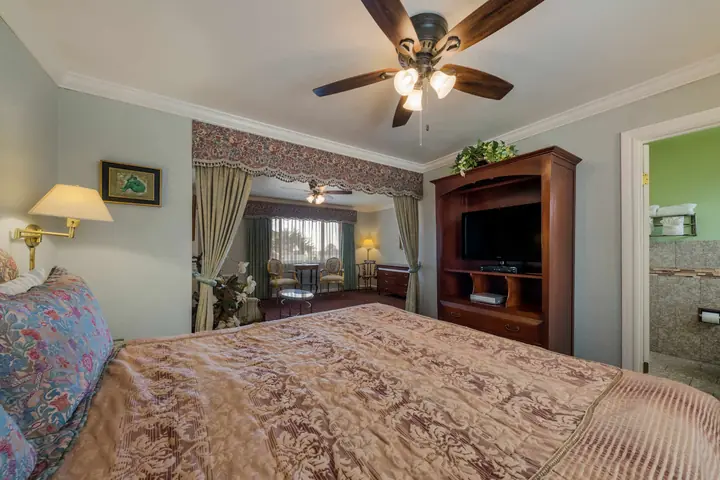 King bed in the suite with an armoire, television and wall lamp