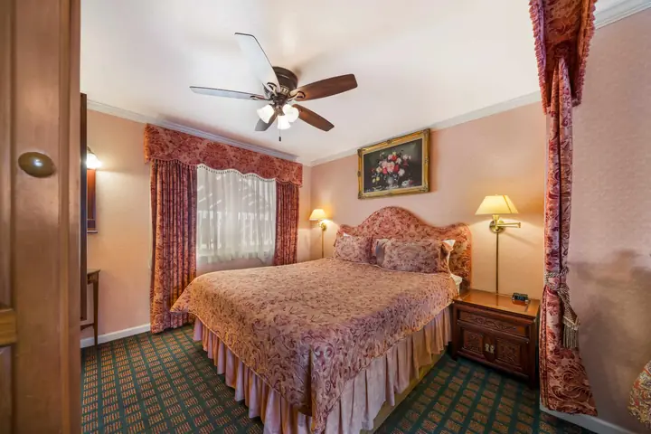 King bedroom in the suite with an upholstered headboard and rose drapes