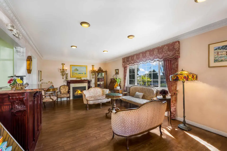 Lobby of Carmel Inn & Suites with a fireplace, carved settees, a stained-glass floor lamp and rose valances