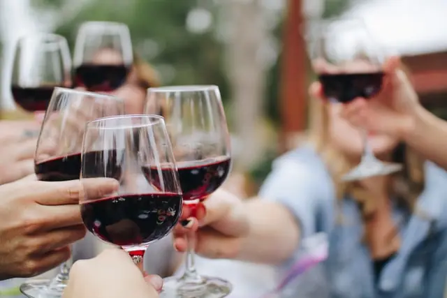 Friends raising glasses of red wine at an outdoor tasting